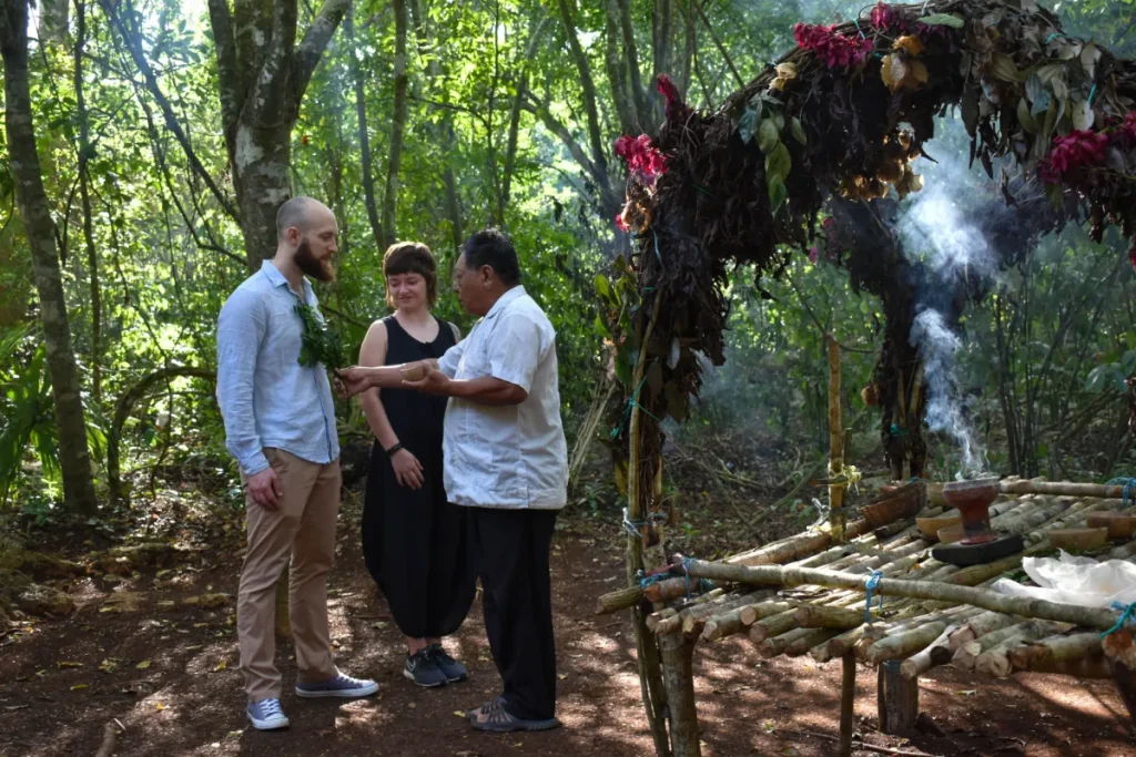 Pareja de turistas participando en ceremonia maya