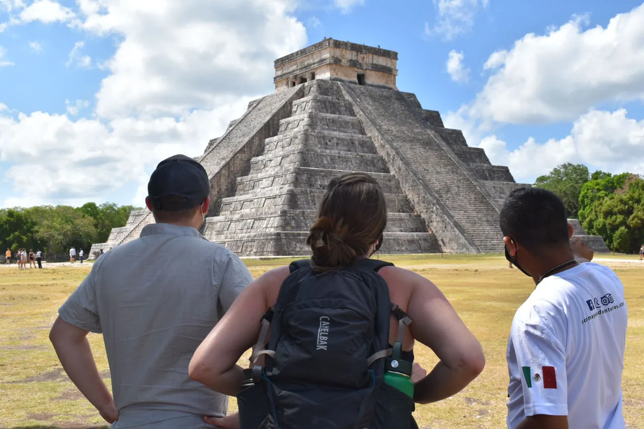 Tres personas viendo la Piramide Chichen Itzá